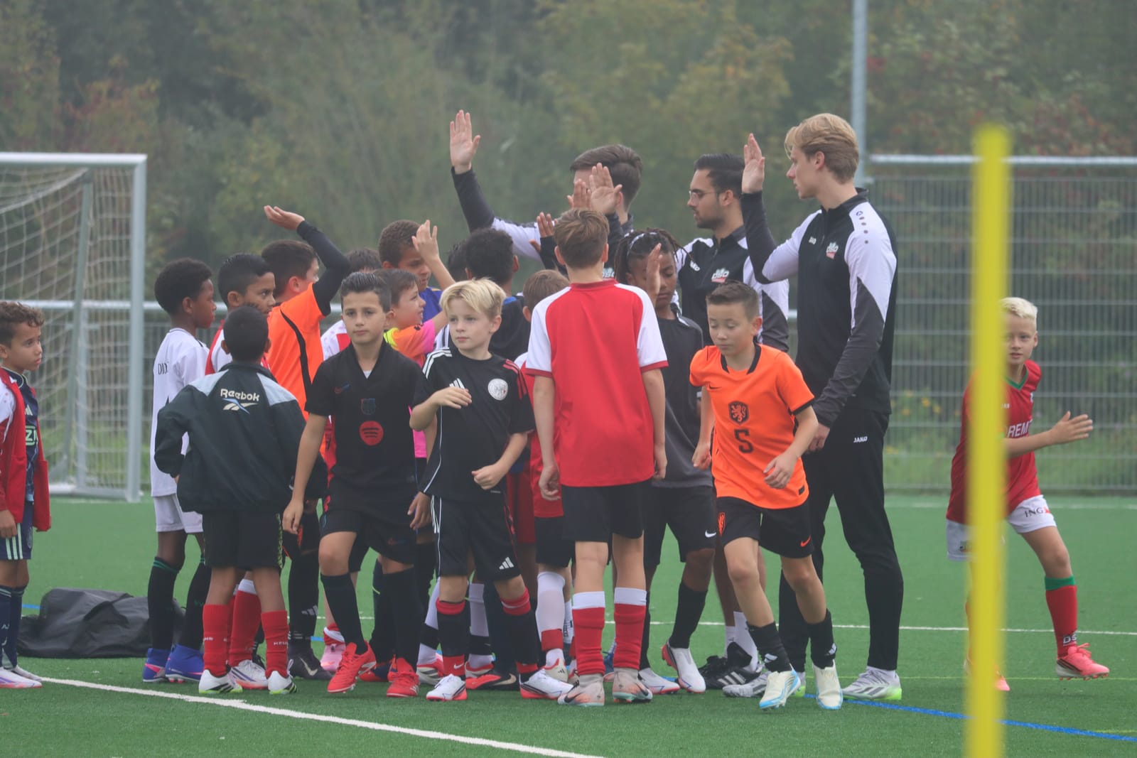 Trainers en spelers geven elkaar een high-five op het veld van sv DSO
